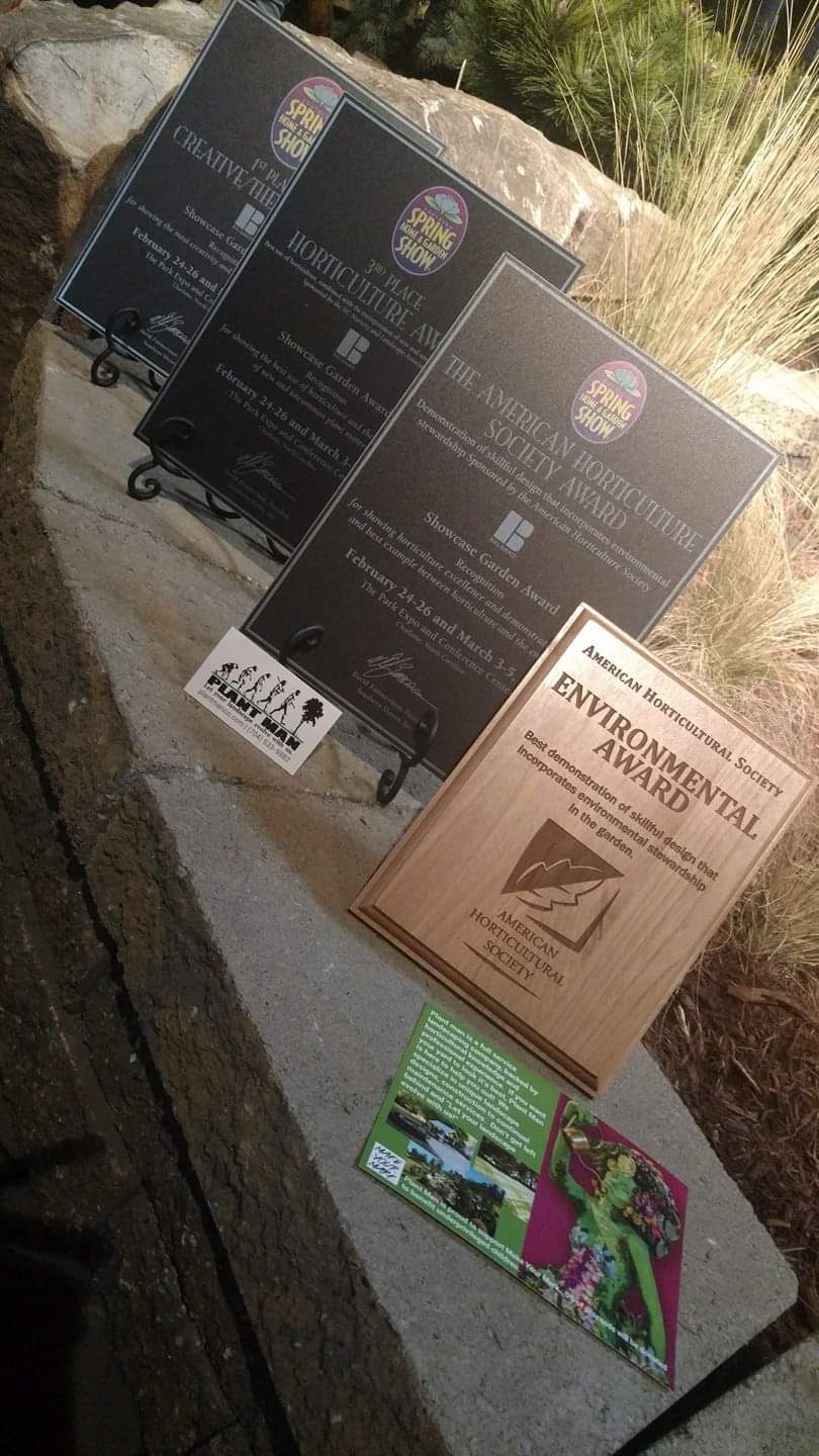 Four award plaques displayed on stone steps at a garden show exhibit, lit at night