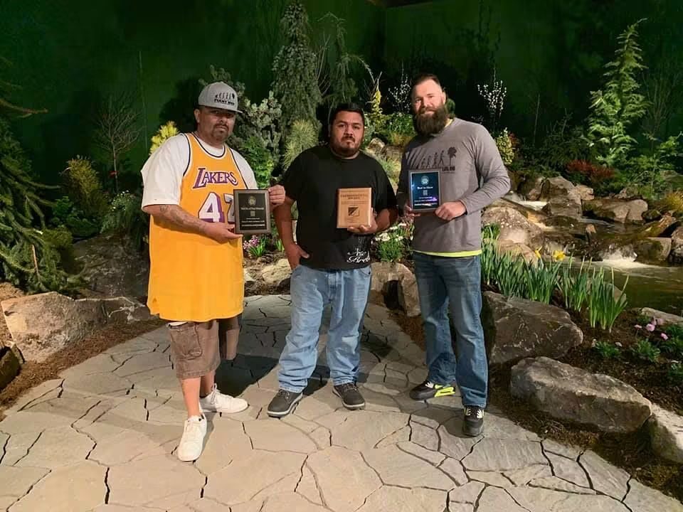 The Plant Man team holding their award plaques on the show garden's stone patio