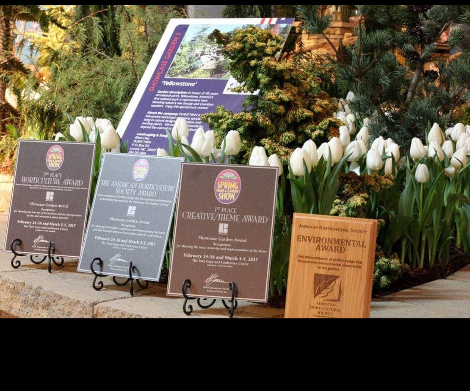 Award plaques beside white tulips and the 'Yellowstone' showcase garden sign at the Southern Spring Home & Garden Show