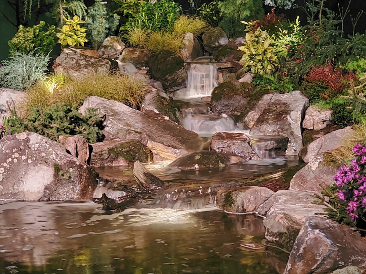 Water cascading over stacked stone into a lit pool