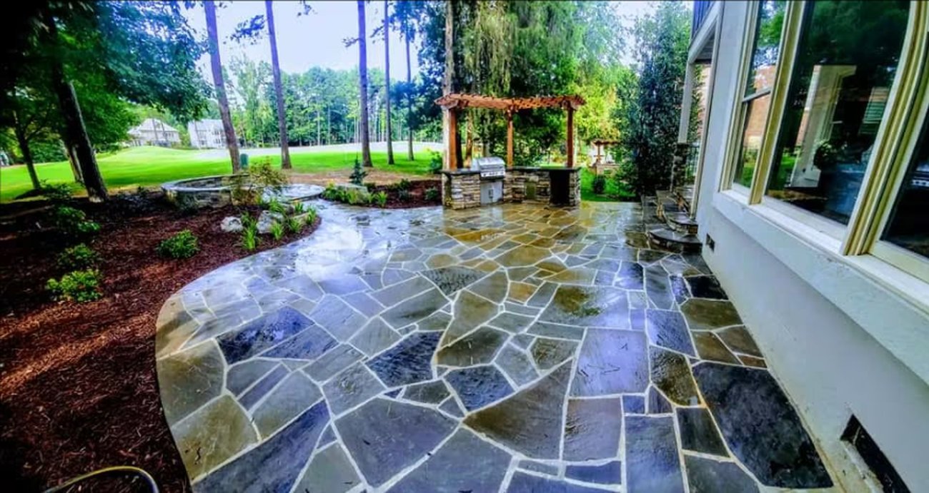 Flagstone patio with a pergola and lawn beyond