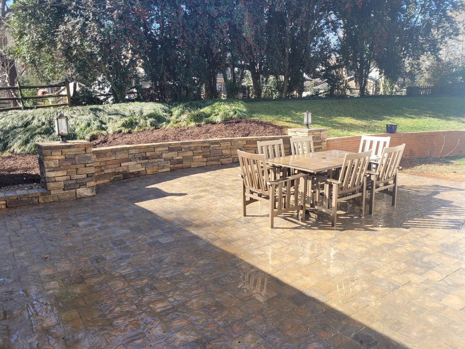 Paver patio with curved stacked-stone seat wall and dining table at the Matthews Mill House project