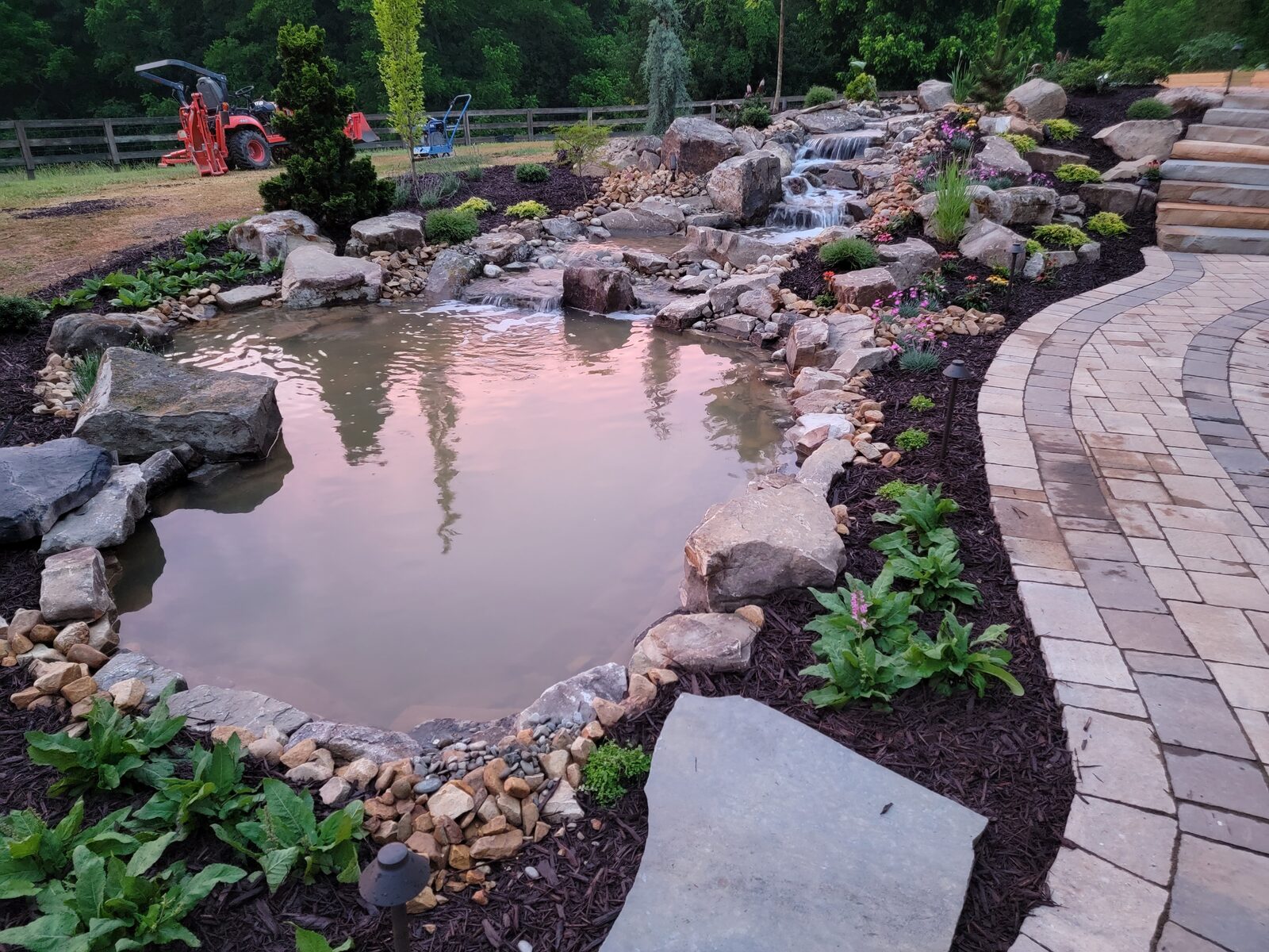 The koi pond and paver path at sunset, with pink sky reflected in the water
