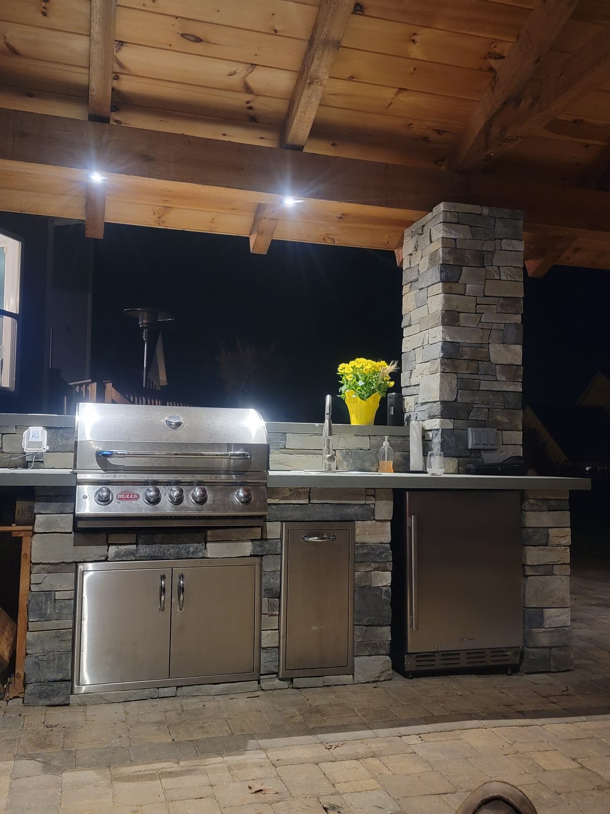 Outdoor kitchen with stainless steel grill built into a pavilion