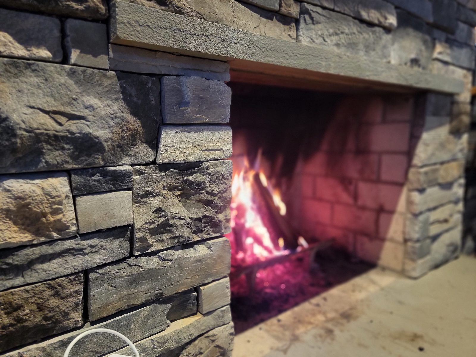 Stacked-stone fireplace detail inside a timber-frame pavilion