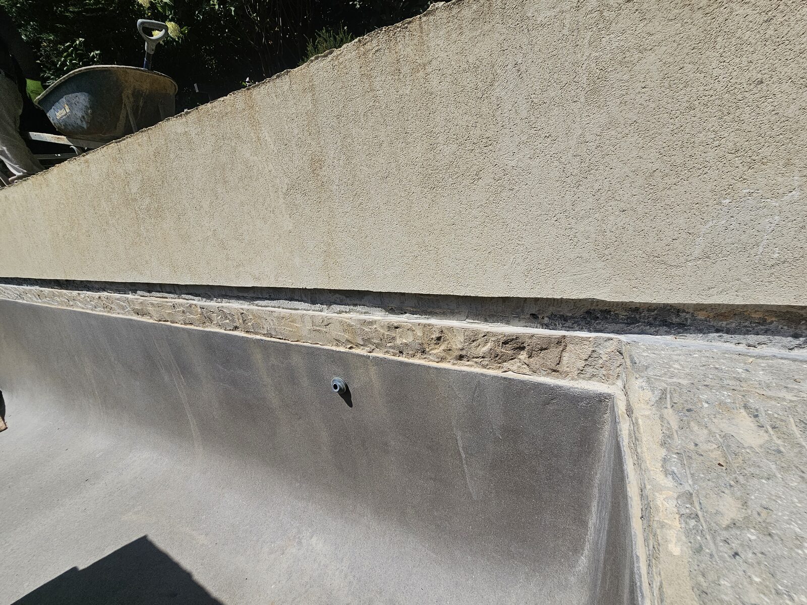 Close detail of the new dimensional limestone coping meeting the pool's black slate waterline during installation