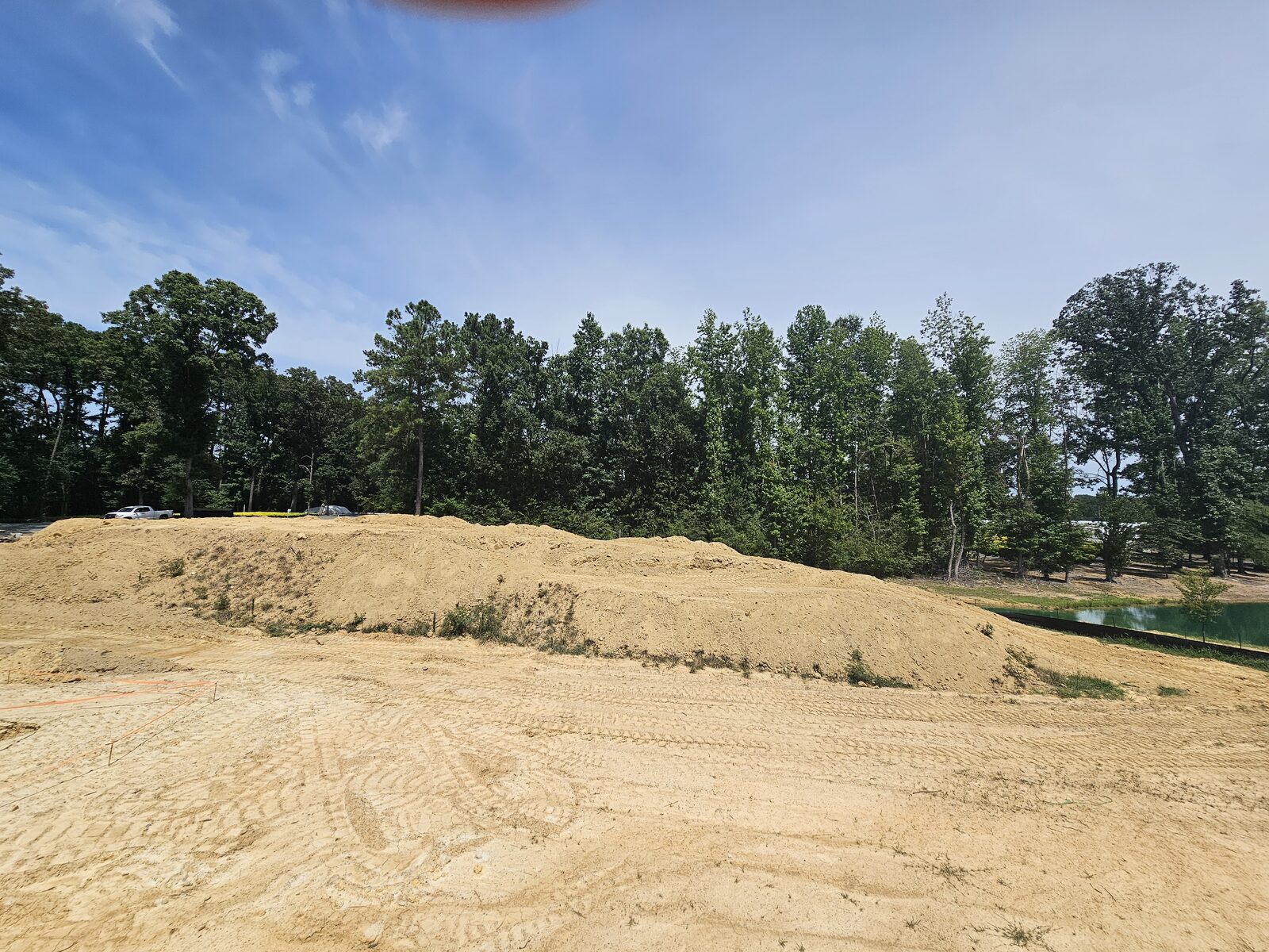 The blank-canvas property before construction, graded soil and sand piles where the water feature would go