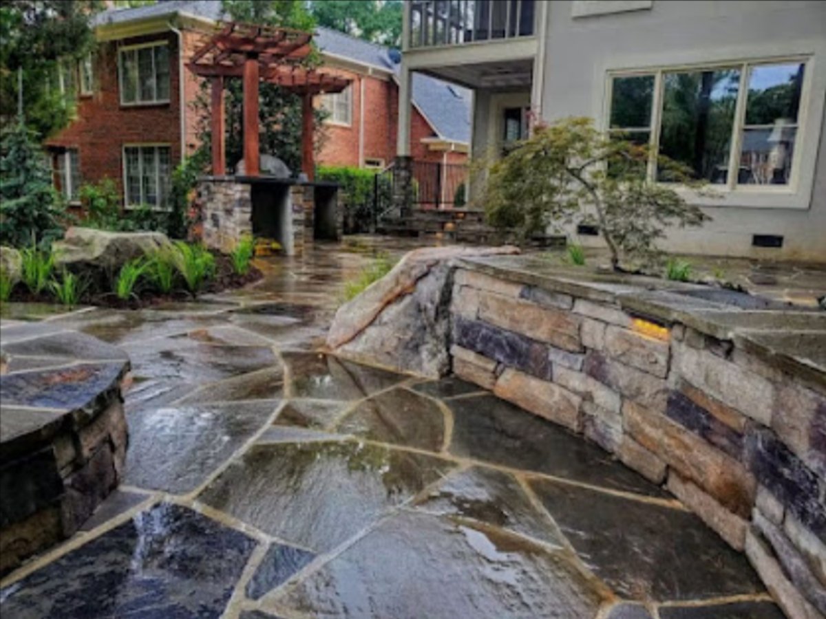 Flagstone patio and stacked-stone wall beside a paved courtyard