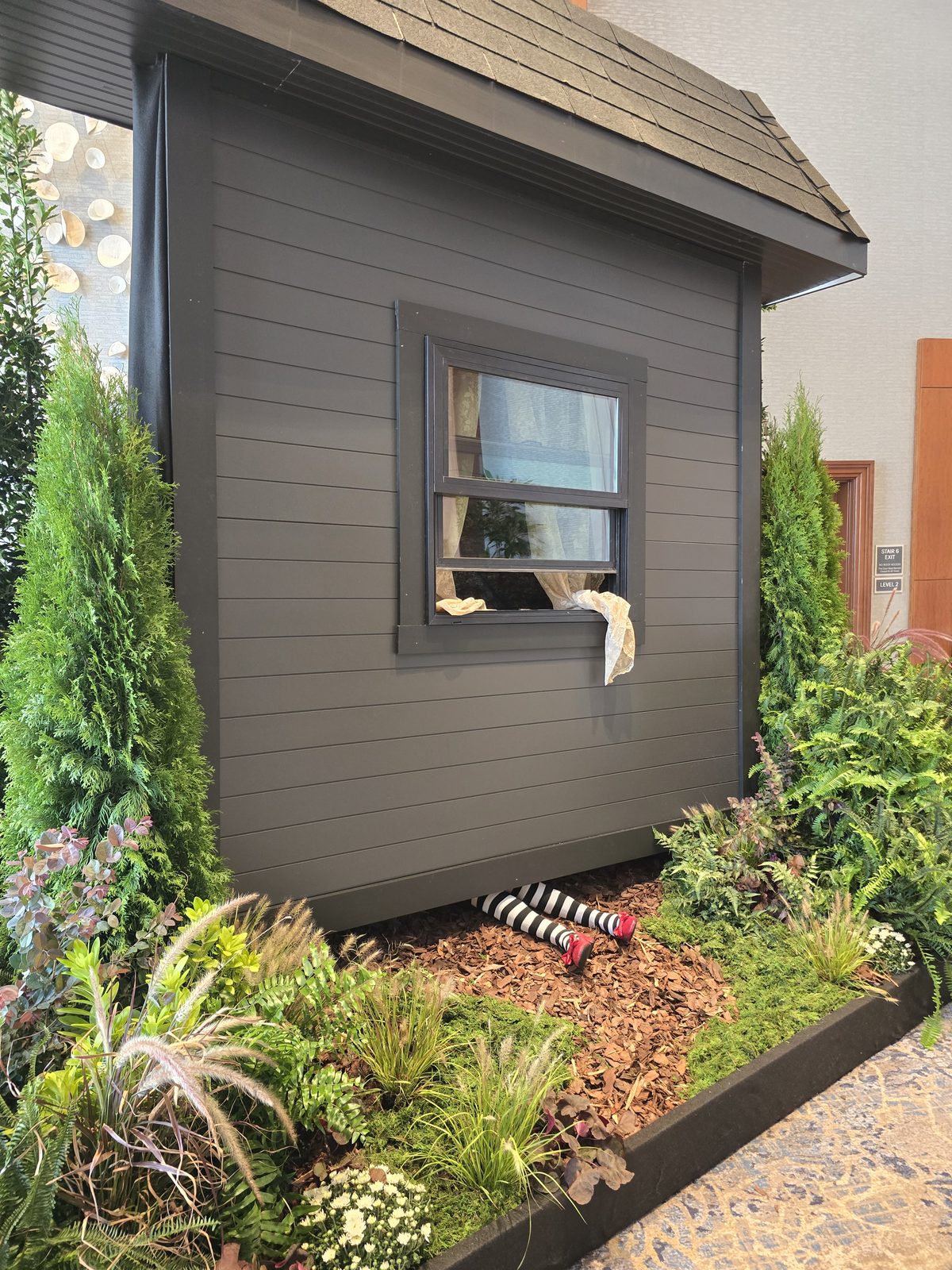 A themed house facade built for the Urban League gala, with the striped legs of a Wizard of Oz witch character visible beneath it in a planted bed