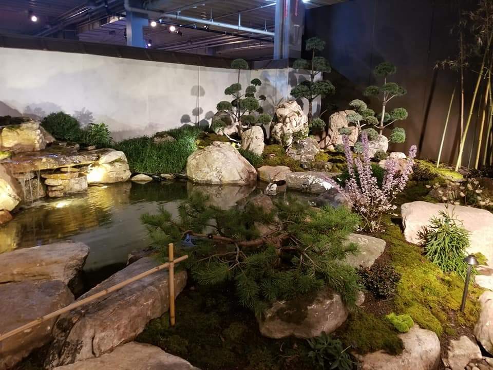 A naturalistic pond with bonsai pines, boulders, and moss, built as a temporary Japanese-style garden