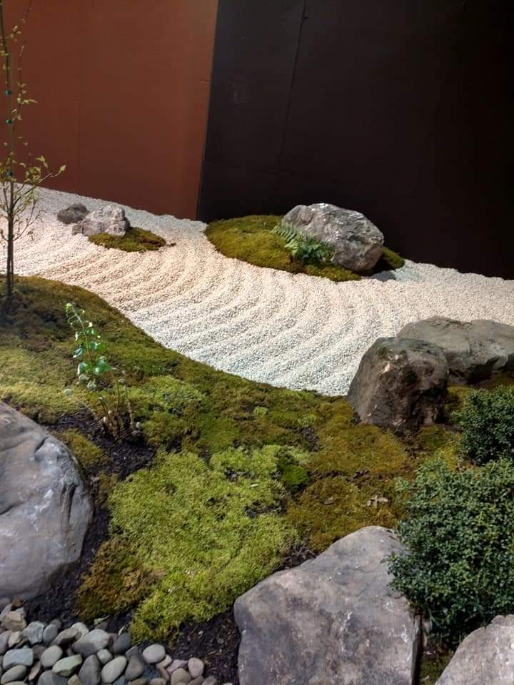 A raked zen sand garden with moss and natural boulders, built as part of a temporary show garden